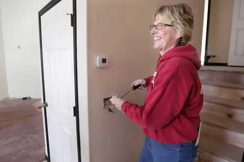 Grace Cummings Pas, owner of Grace Electric, installing wiring in a home