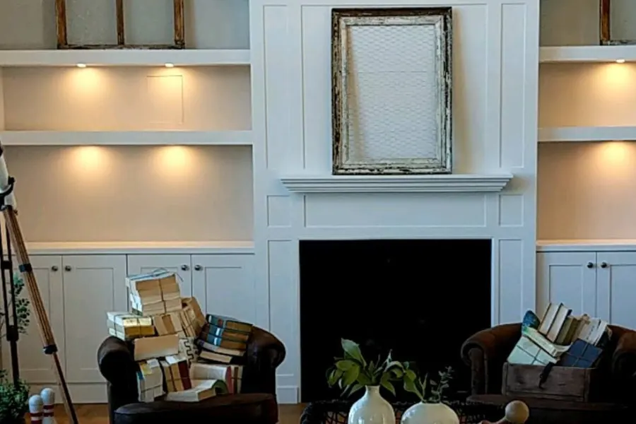 Living room built-ins with warm lights under each shelf beside a fireplace